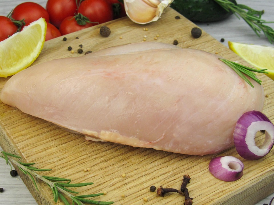 Dada ayam mentah di atas talenan kayu